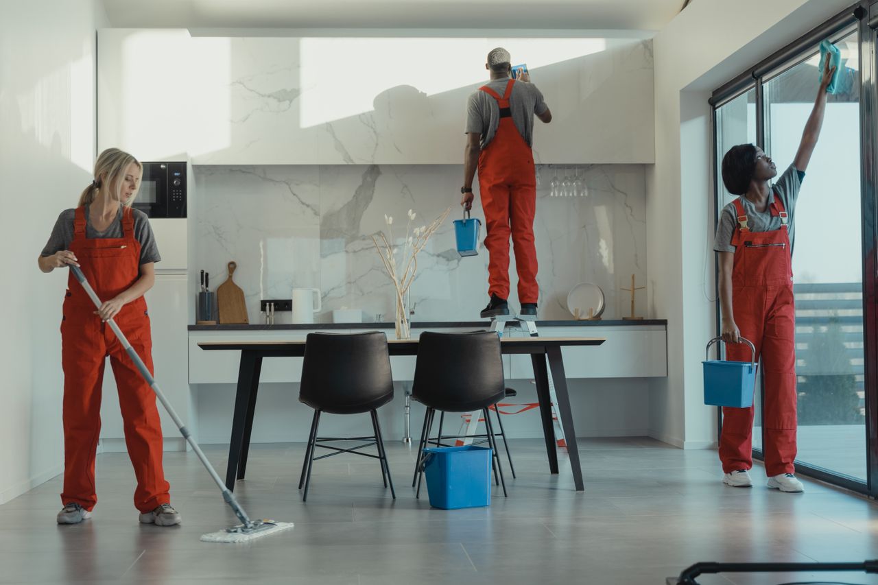 services-02 Group of cleaners in red uniforms mopping and wiping glass in a modern dining room.
